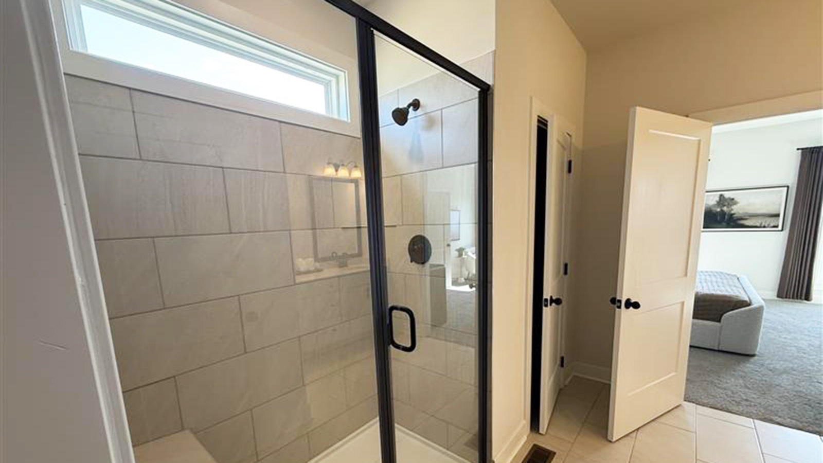 Primary bathroom with dual vanities and tile walk-in shower with glass walls.