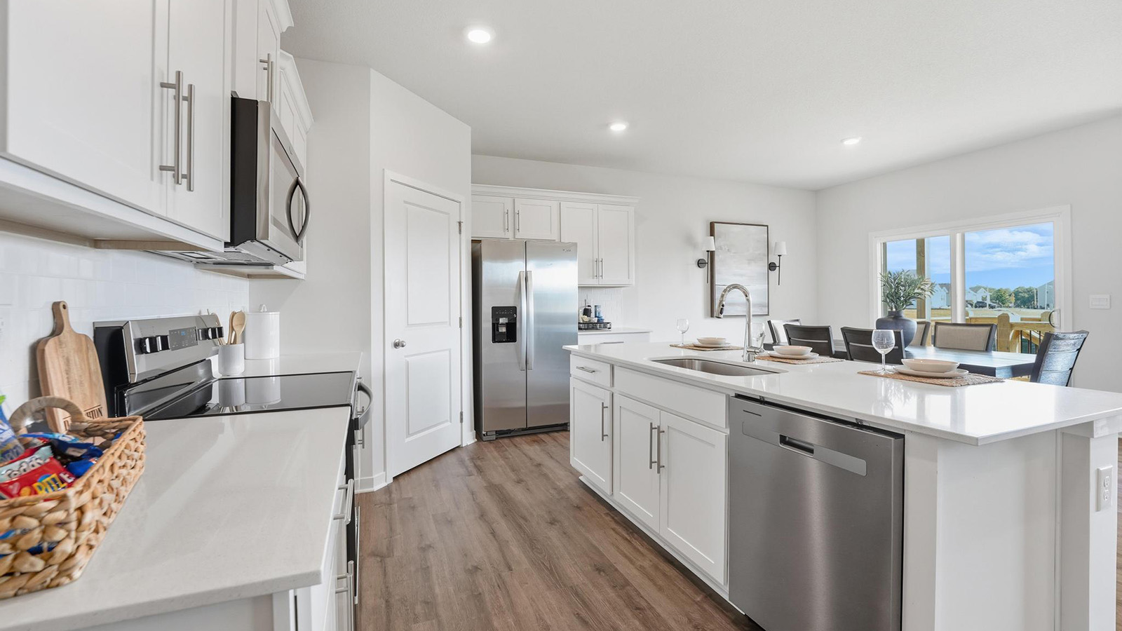 Kitchen and island with white cabinets, tile backsplash, and stainless steel appliances