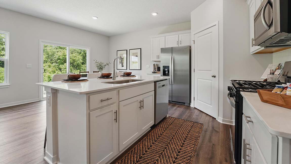 Kitchen and island with white cabinets and stainless steel appliances.
