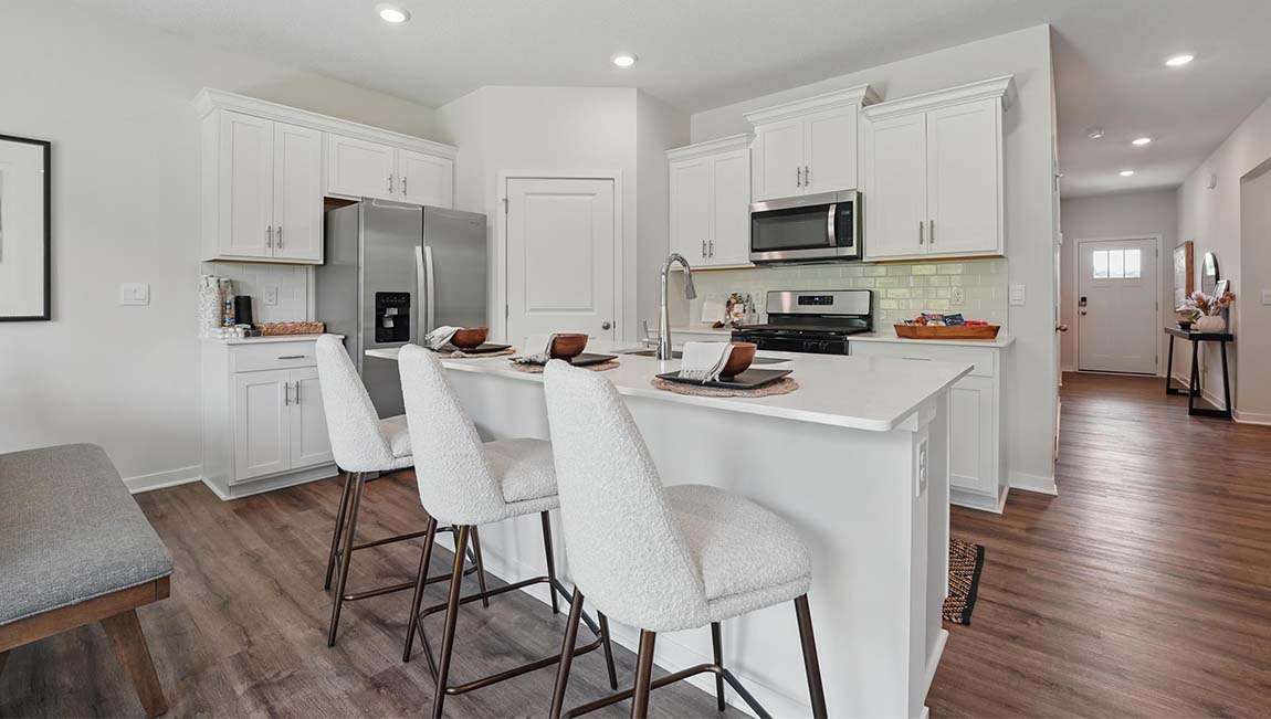 Kitchen and island with white cabinets and stainless steel appliances.