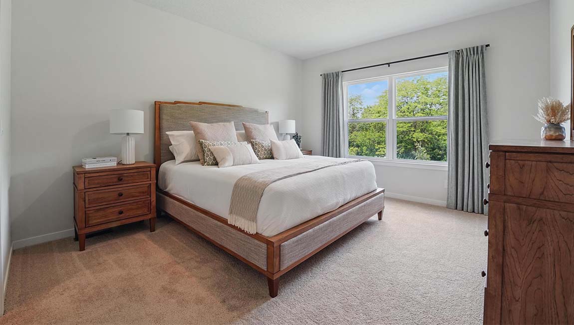 Carpeted primary bedroom with large window.