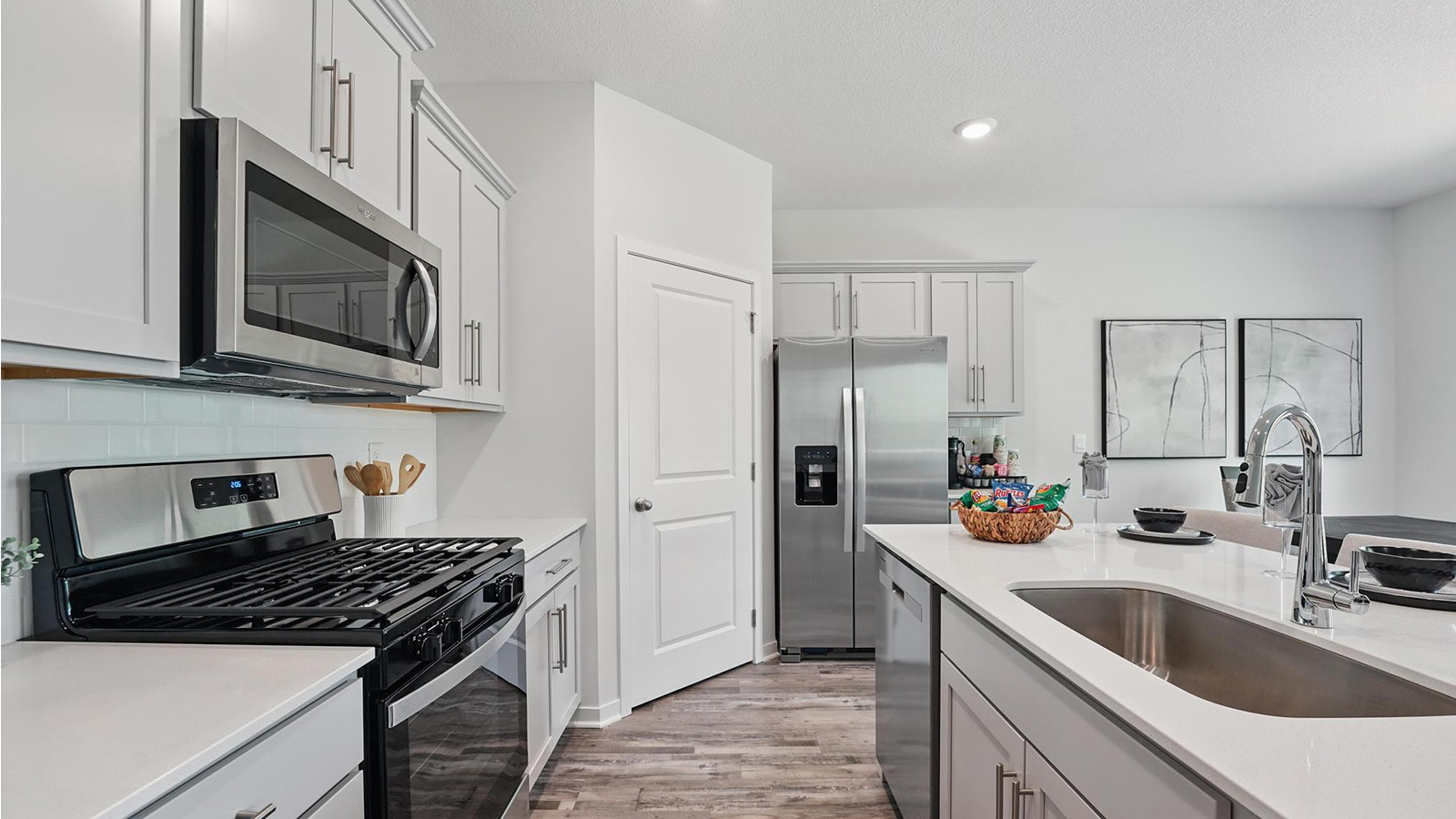 Kitchen and island with gray cabinets and stainless steel appliances.