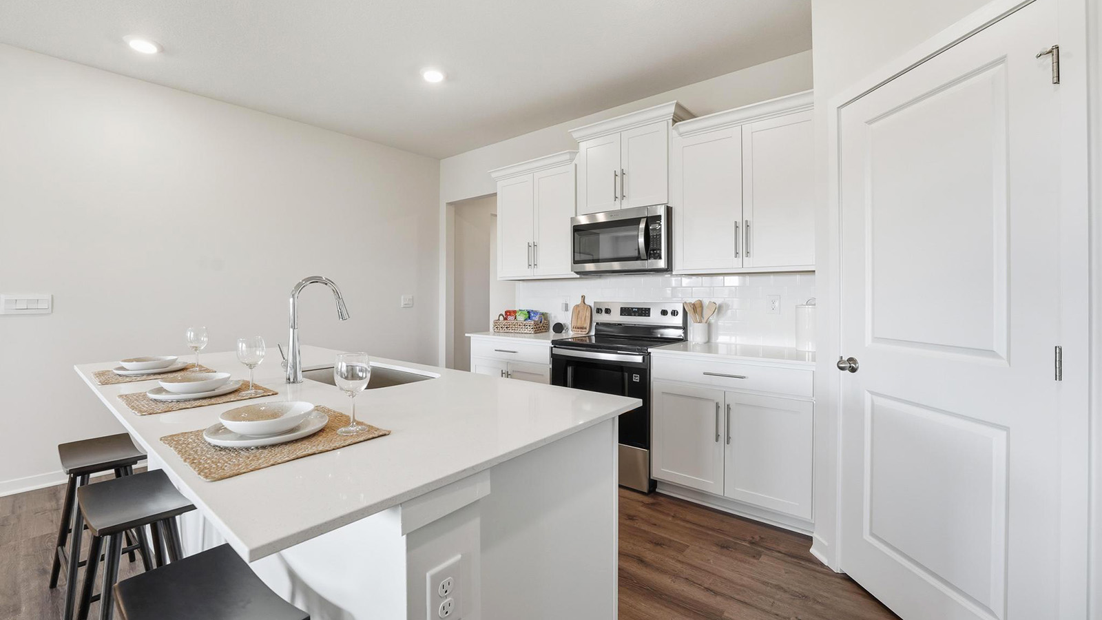 Kitchen and island with white cabinets, tile backsplash, and stainless steel appliances