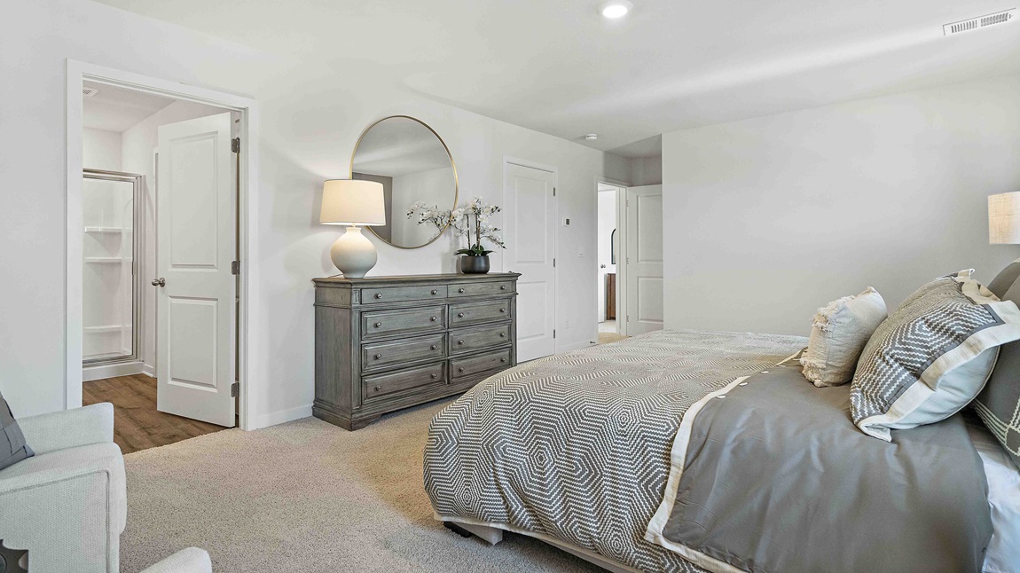 Carpeted primary bedroom with large windows and seating area.