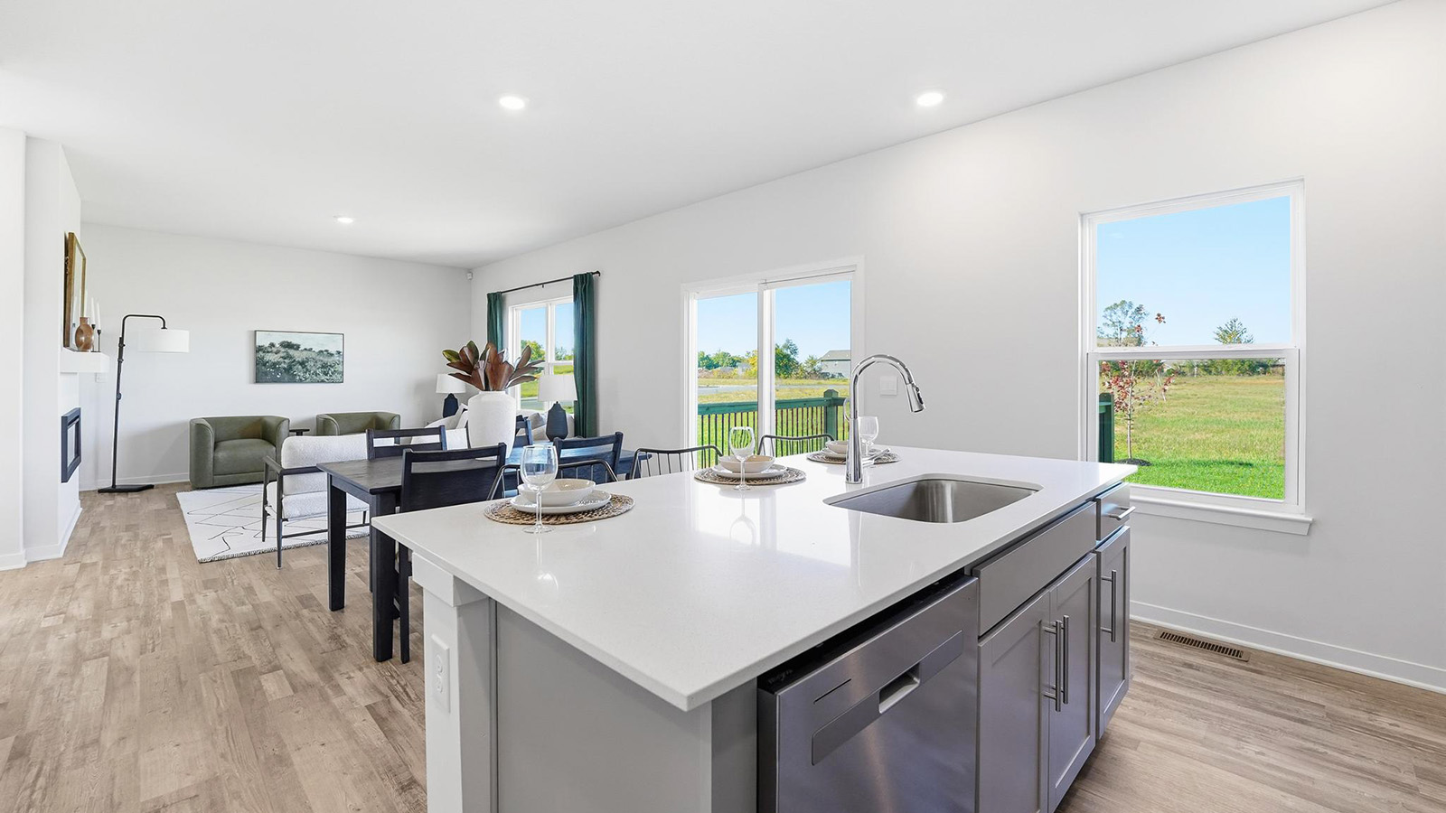 Kitchen and island with white cabinets and stainless steel appliances.