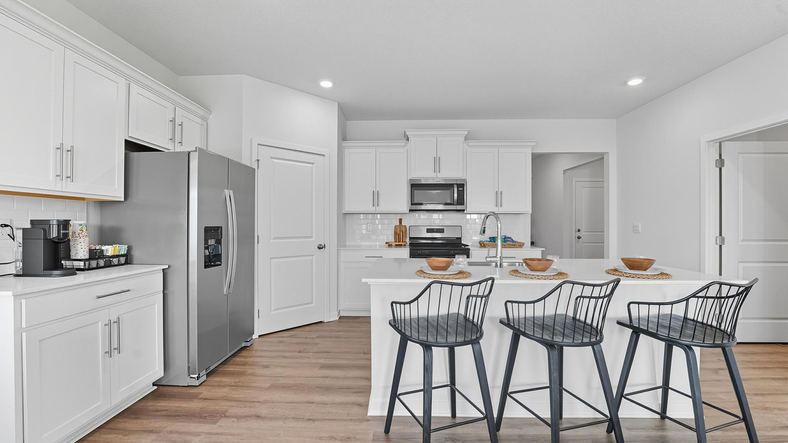 Kitchen and island with white cabinets and stainless steel appliances.