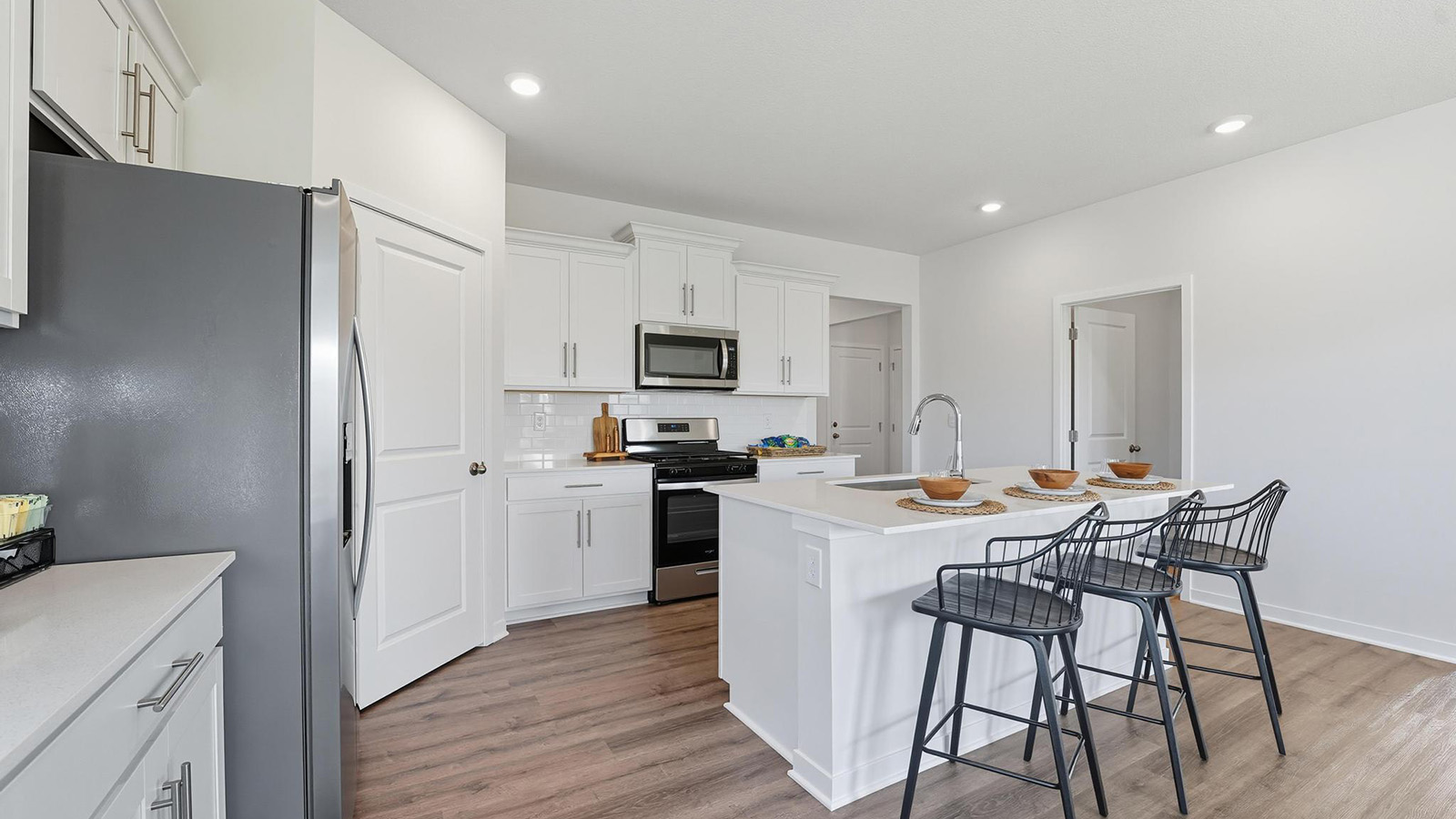 Kitchen and island with white cabinets and stainless steel appliances.