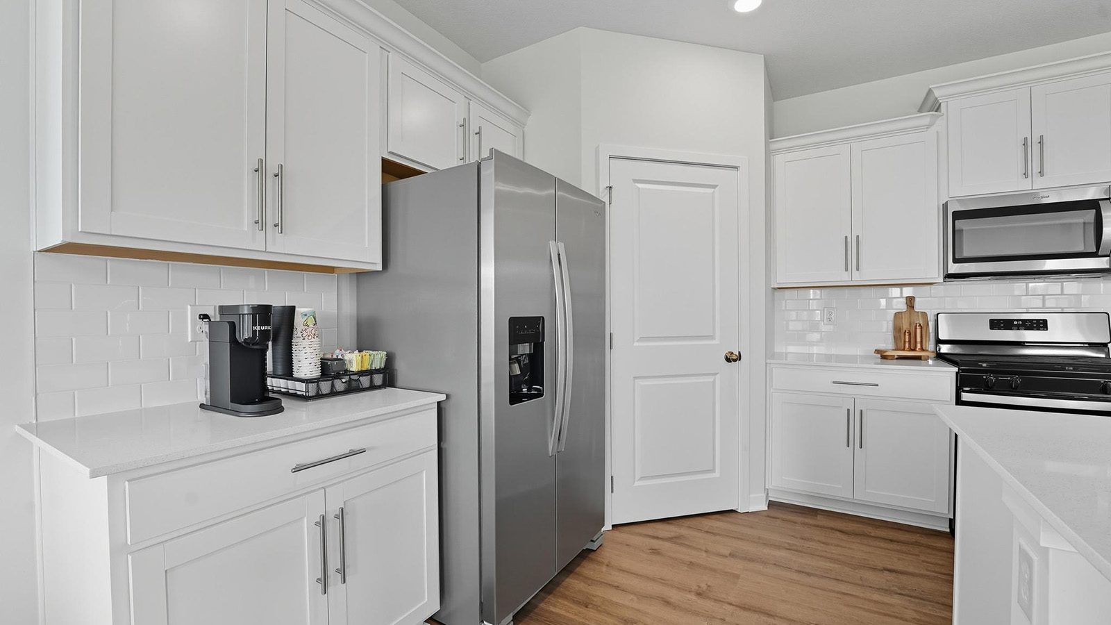 Kitchen and island with white cabinets and stainless steel appliances.