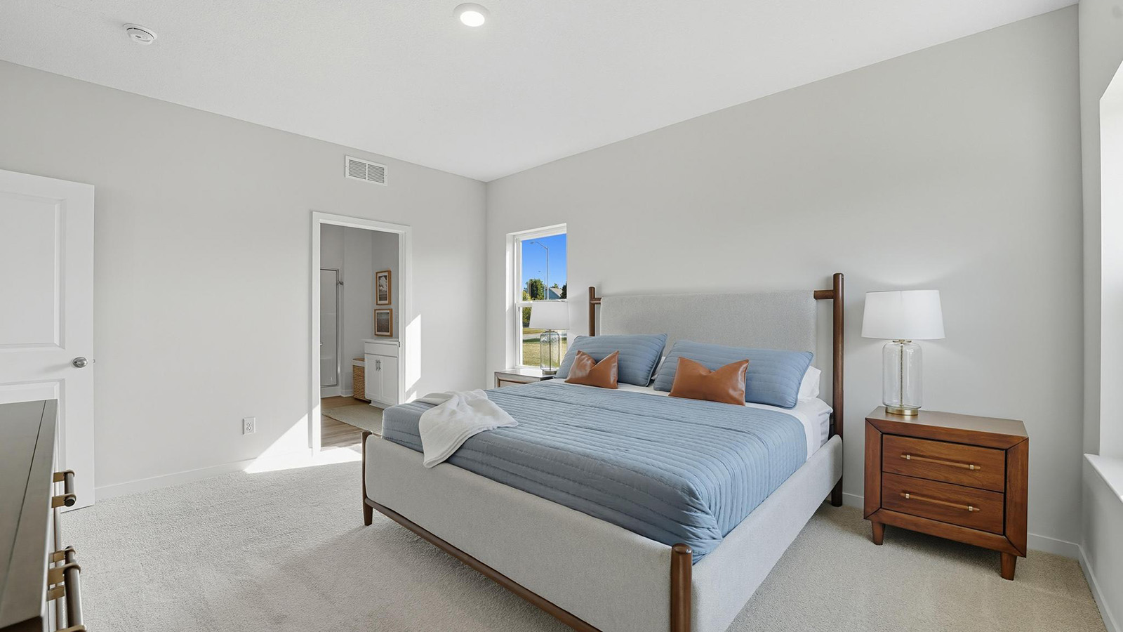 Carpeted primary bedroom with large windows.