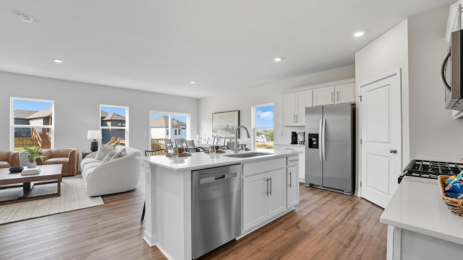Kitchen and island with white cabinets and stainless steel appliances.