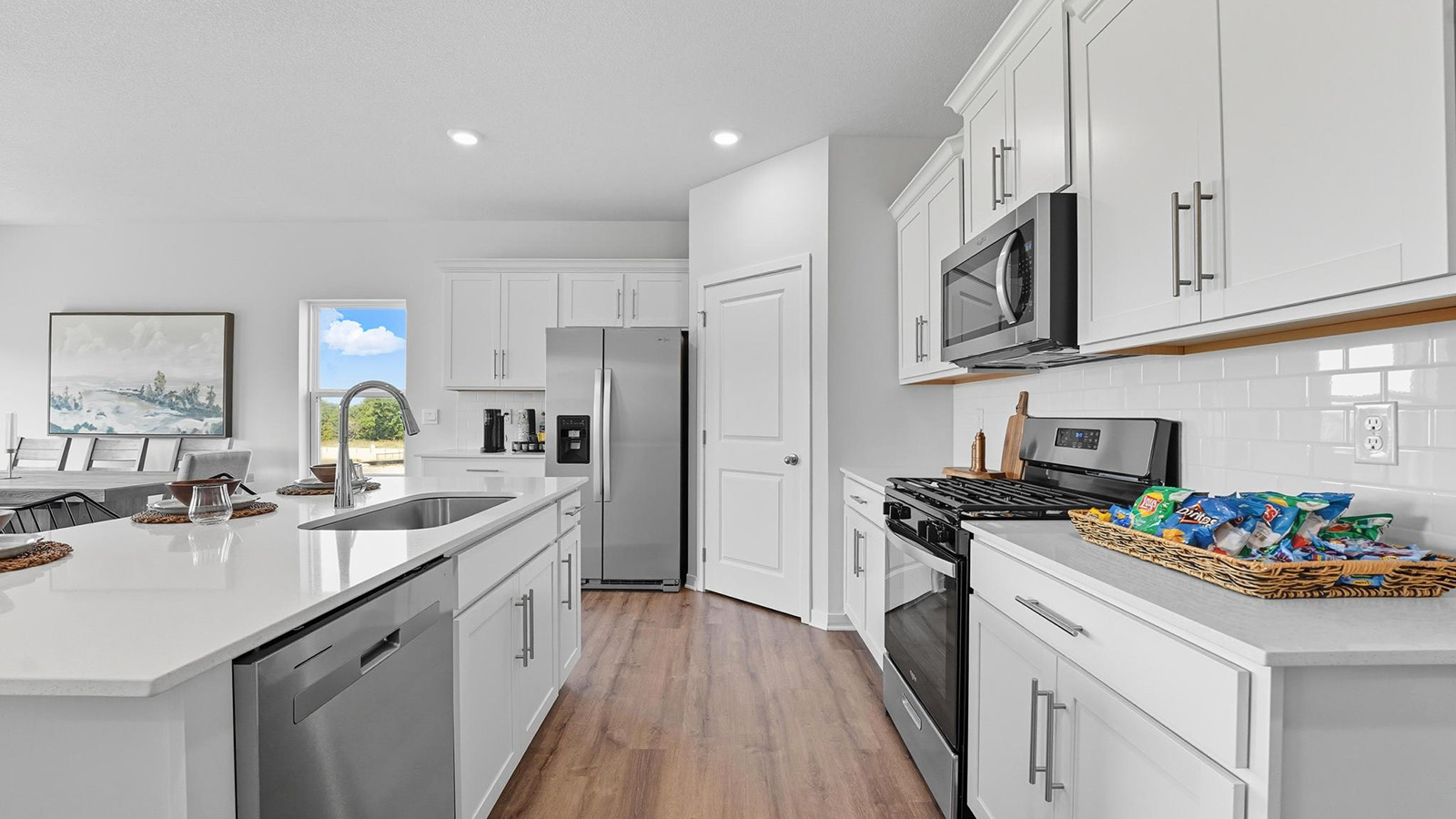 Kitchen and island with white cabinets and stainless steel appliances.