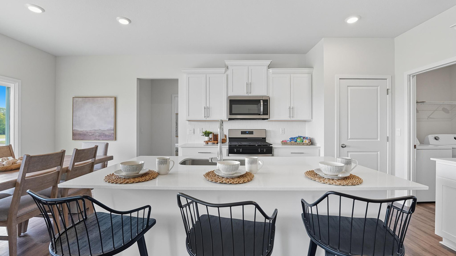 Open-concept kitchen with white counters and cabinets, and stainless steel appliances