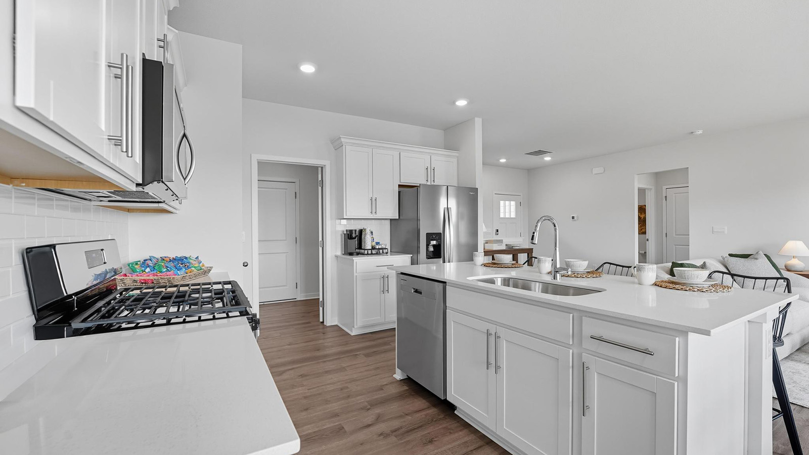 Open-concept kitchen with white counters and cabinets, and stainless steel appliances.