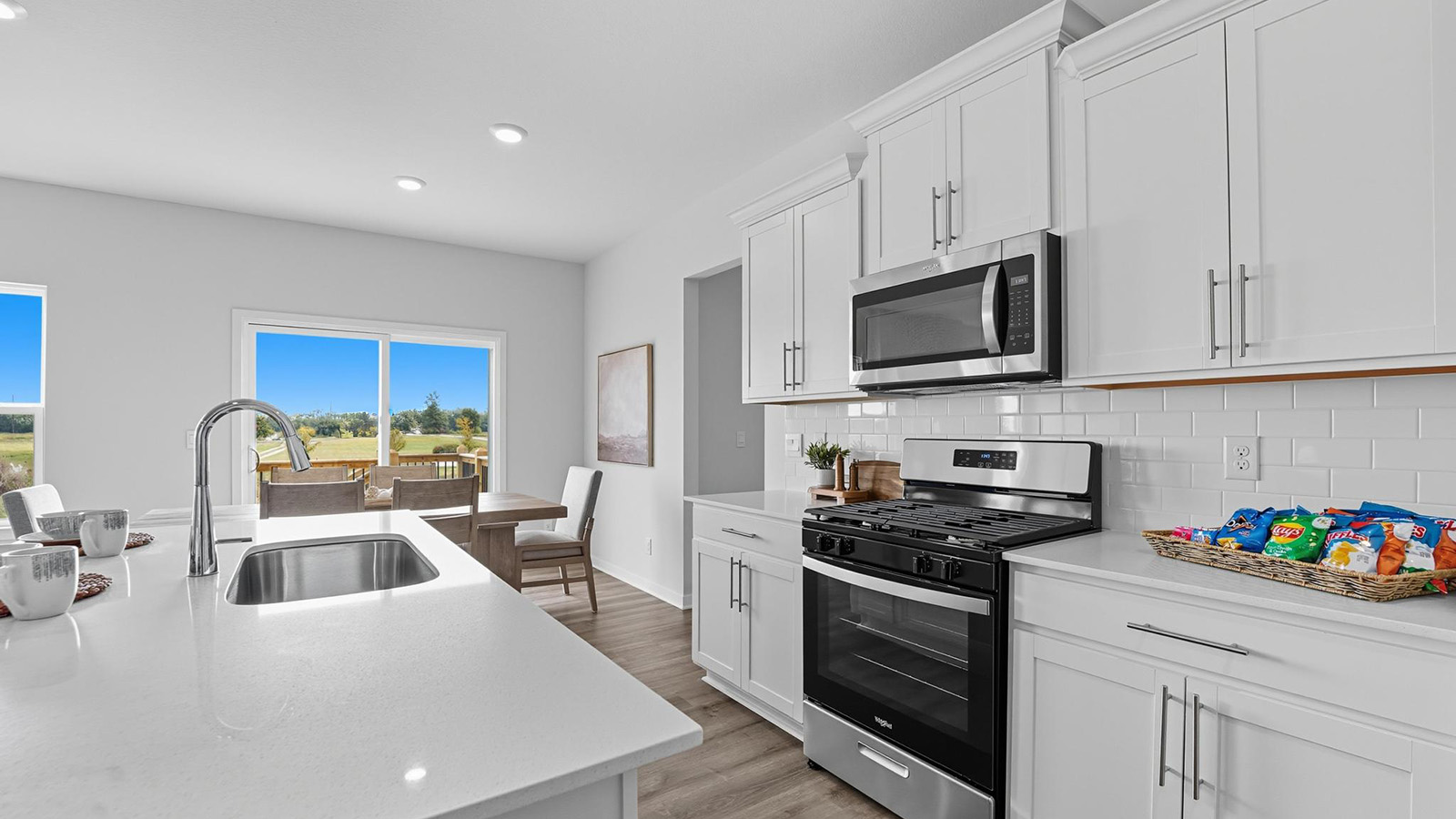 Open-concept kitchen with white counters and cabinets, and stainless steel appliances