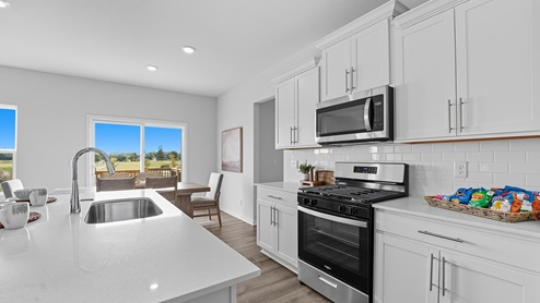 Open-concept kitchen with white counters and cabinets, and stainless steel appliances