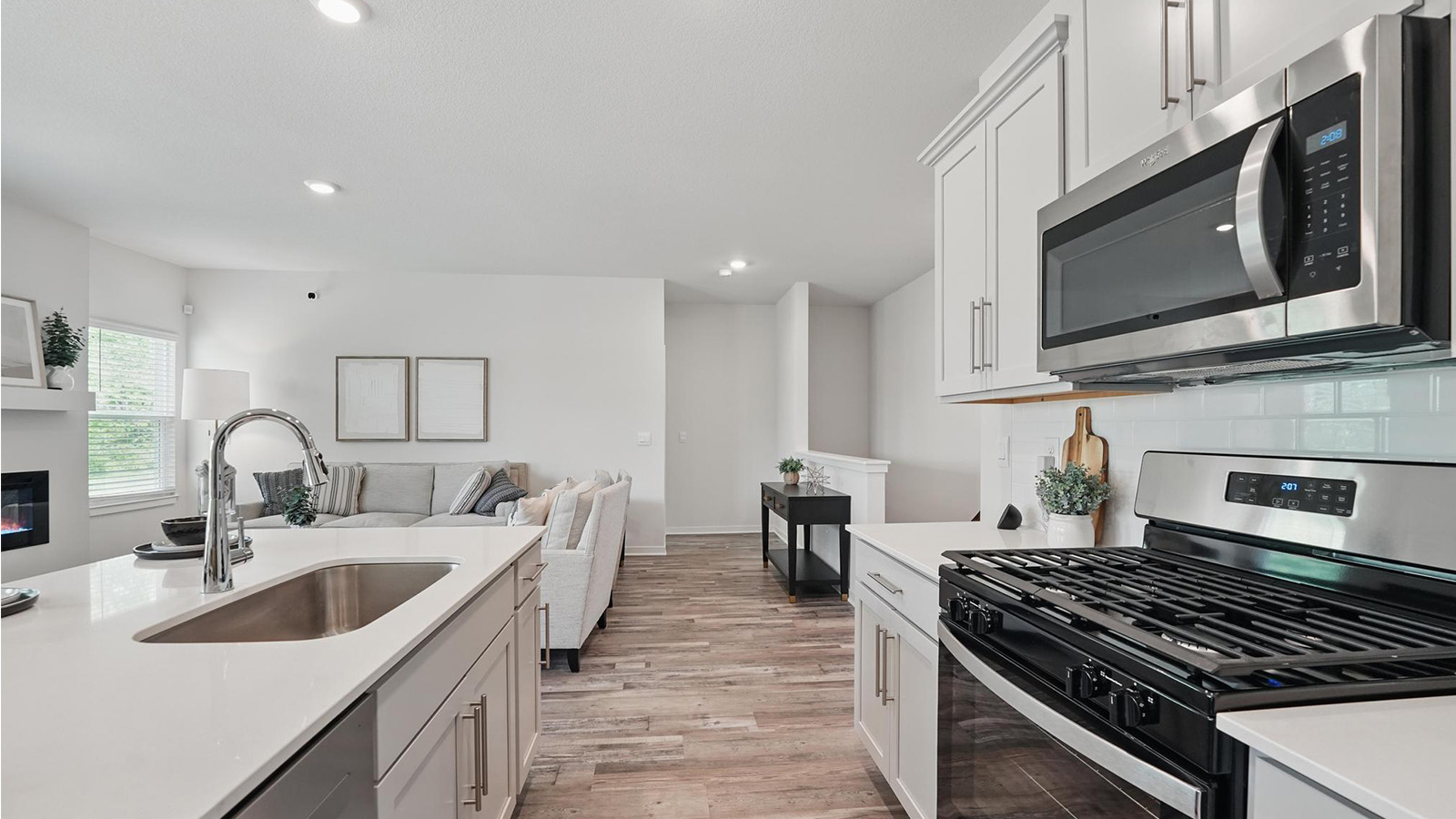 Kitchen and island with gray cabinets and stainless steel appliances. New Homes in Kansas City, Missouri