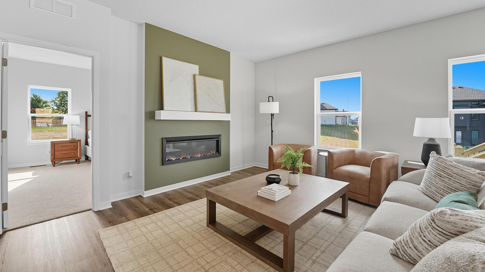 Living room with electric fireplace and two large windows, beside kitchen and dining area