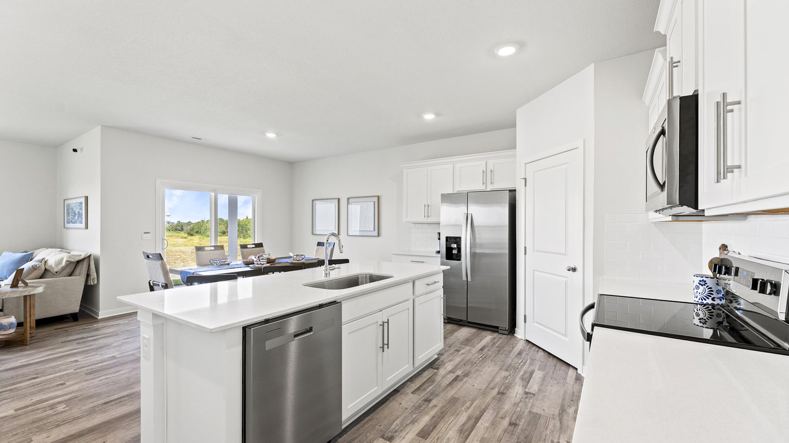 Kitchen and island with white cabinets, tile backsplash, and stainless steel appliances