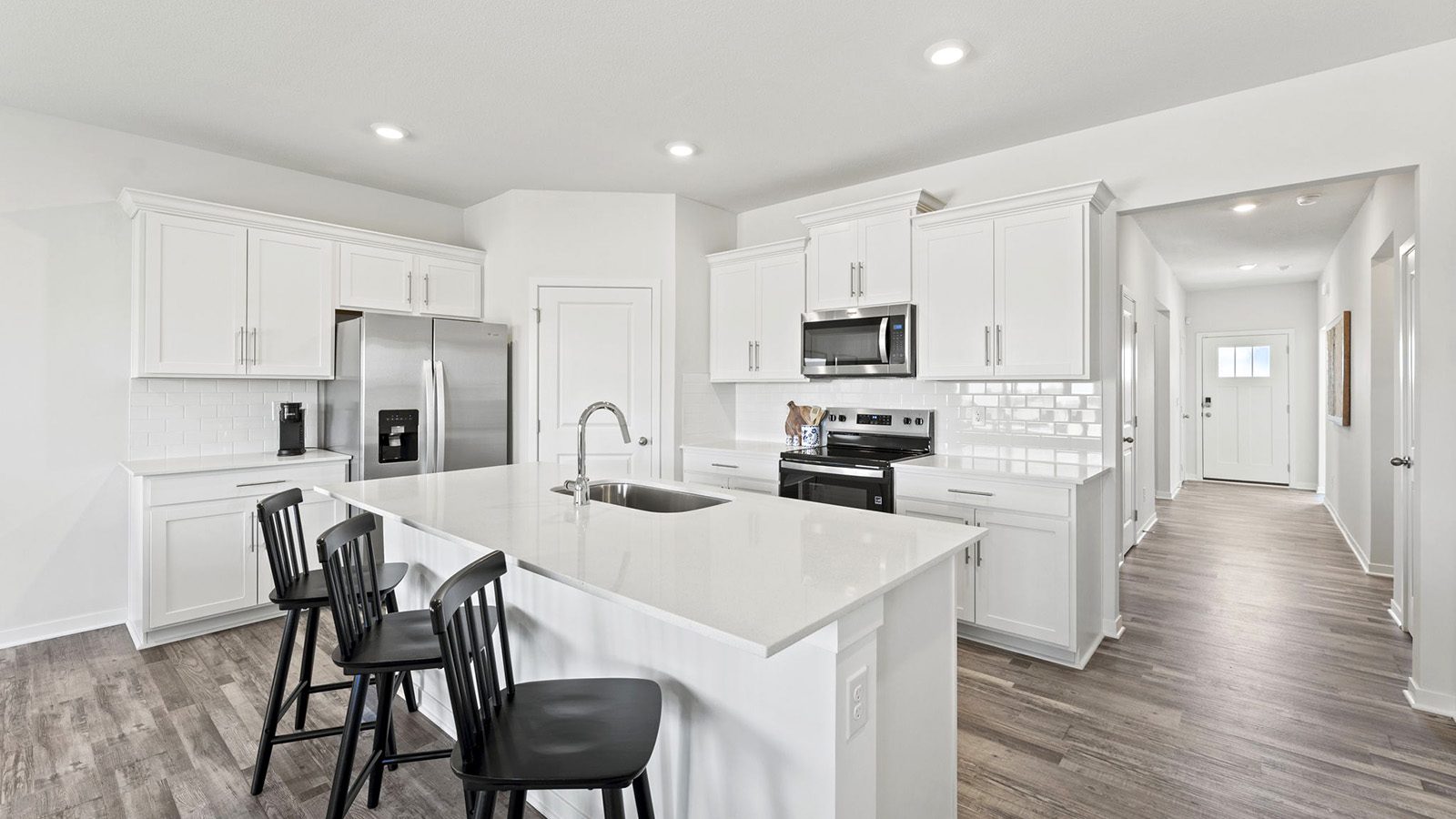 Kitchen and island with white cabinets, tile backsplash, and stainless steel appliances