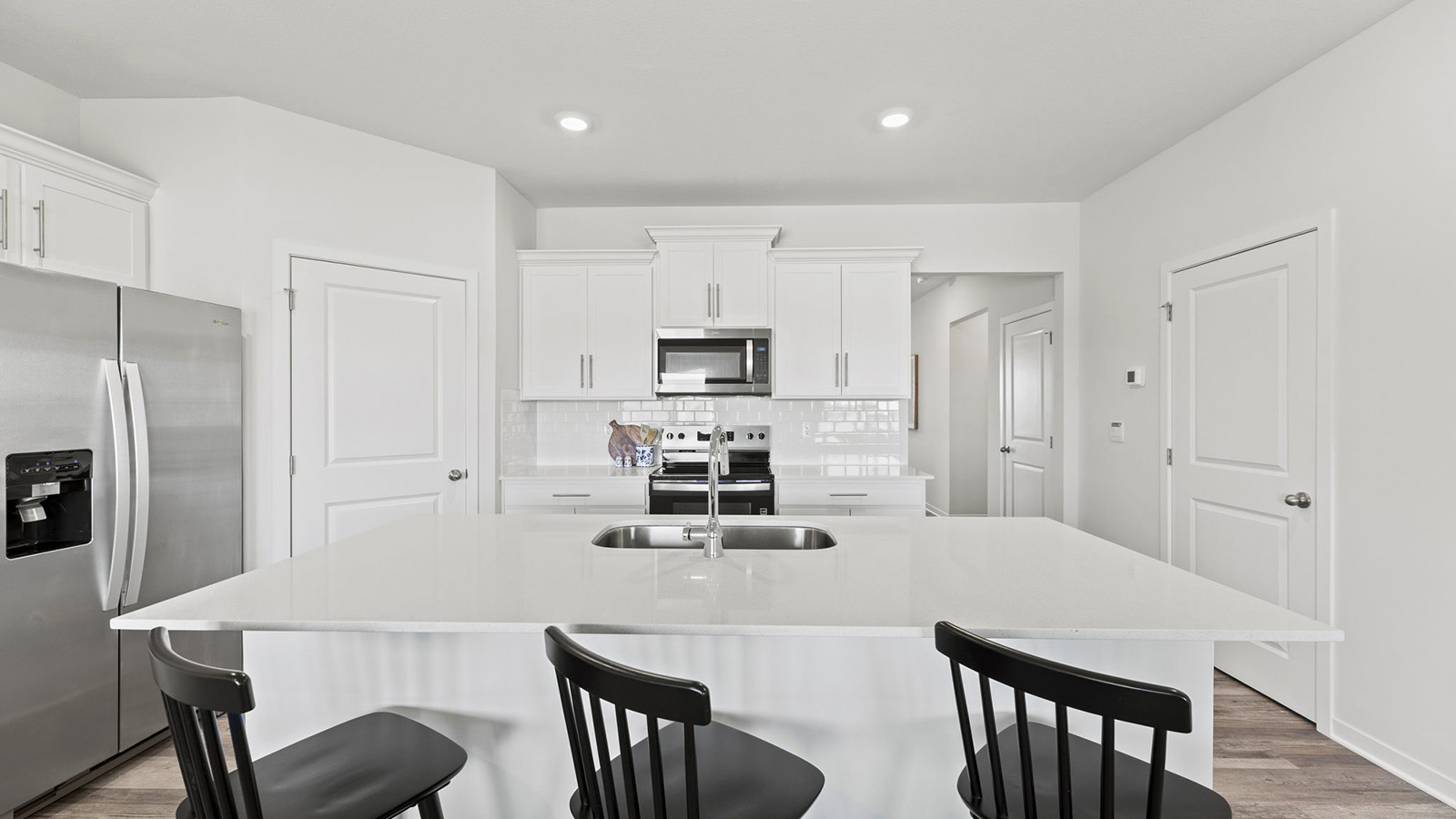 Kitchen and island with white cabinets, tile backsplash, and stainless steel appliances