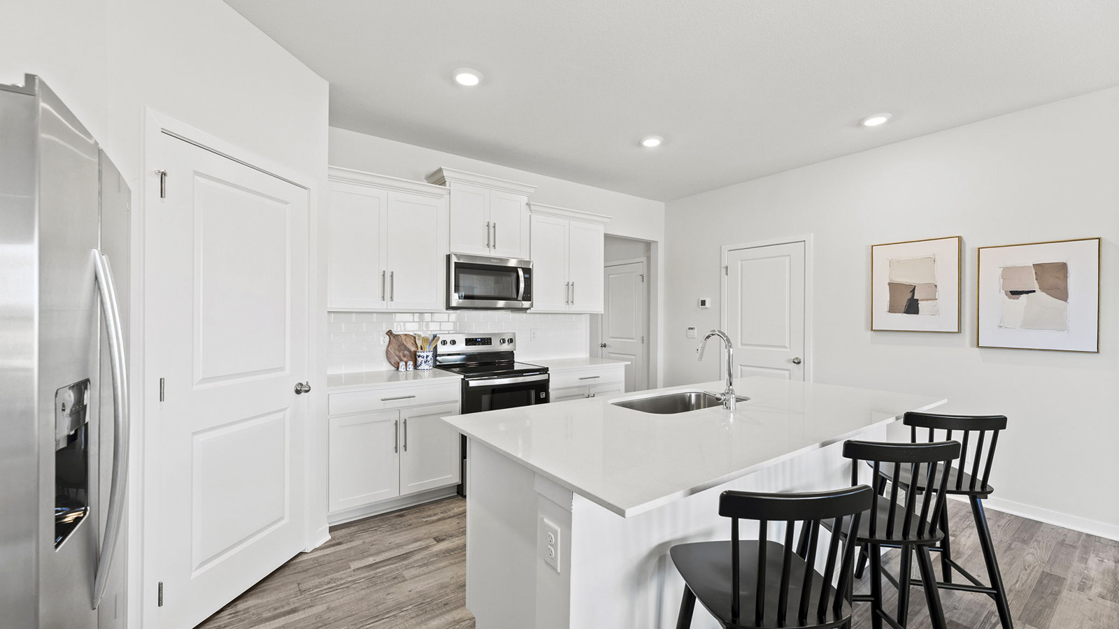 Kitchen and island with white cabinets, tile backsplash, and stainless steel appliances