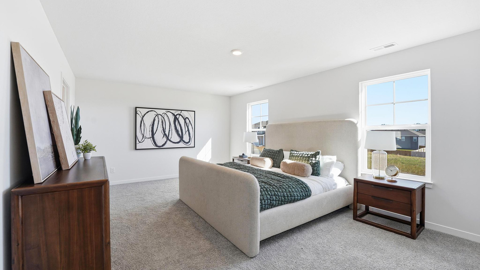 Carpeted primary bedroom with large windows and seating area.