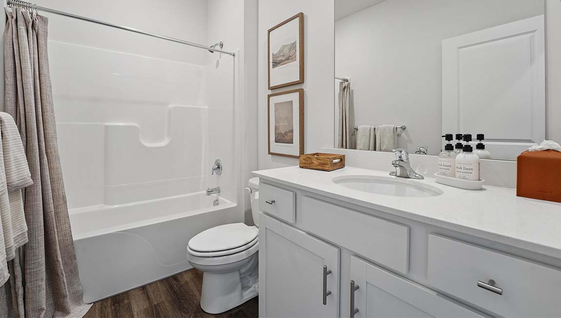 Bathroom with double sink vanity, standing glass door shower, and entryway to the walk in closet