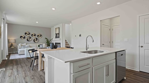 Kitchen and island with white cabinets and stainless steel appliances. New Homes in Kansas City, Missouri