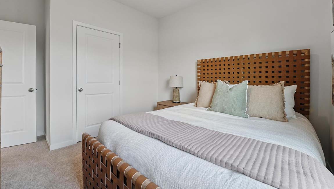 Carpeted bedroom with large window.
