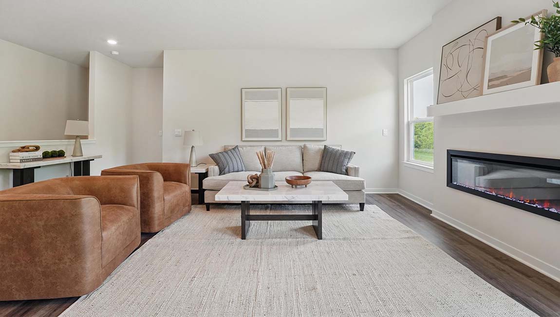 Living room with electric fireplace and two large windows, beside kitchen and dining area.