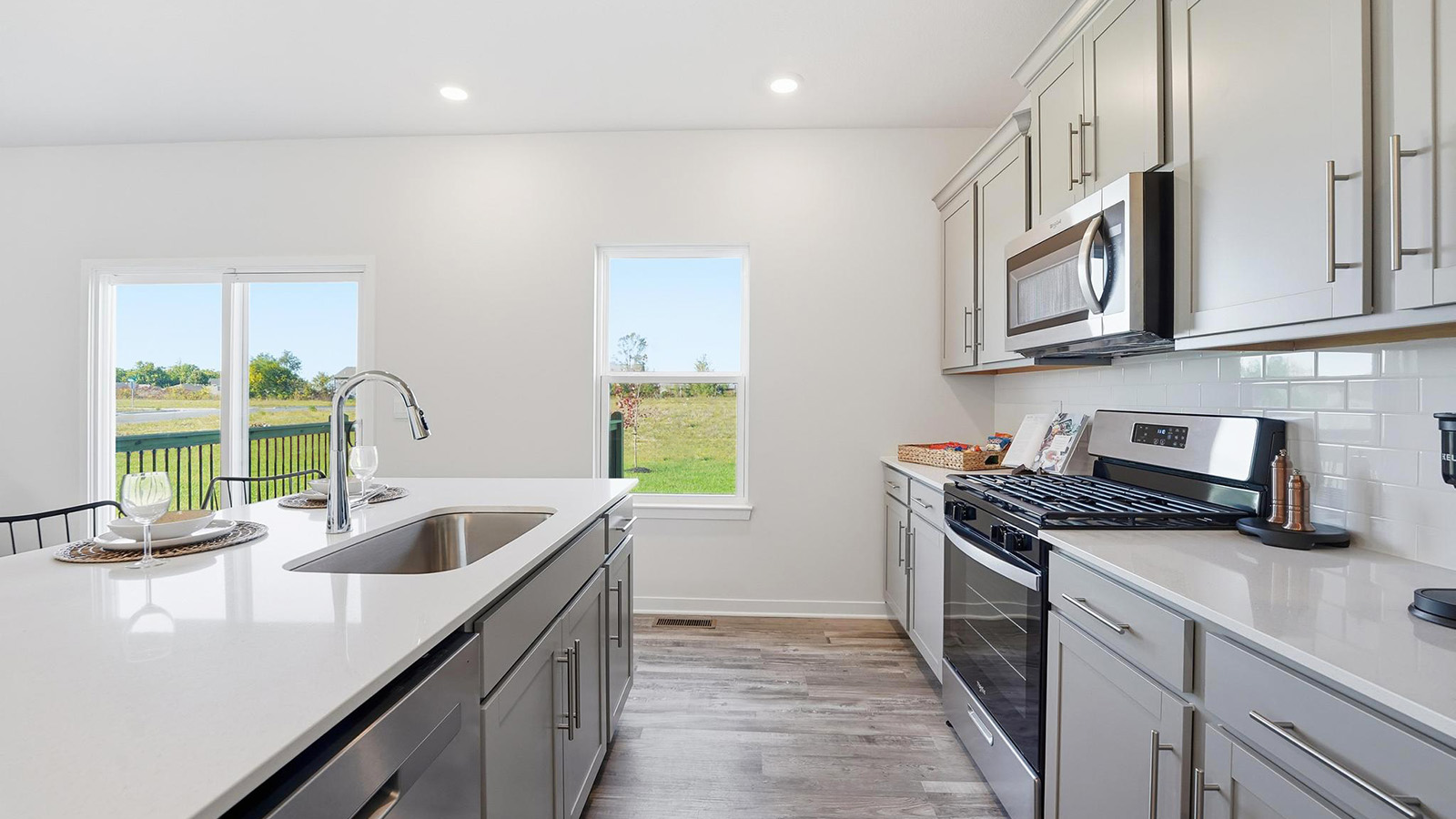 Kitchen and island with white cabinets and stainless steel appliances.