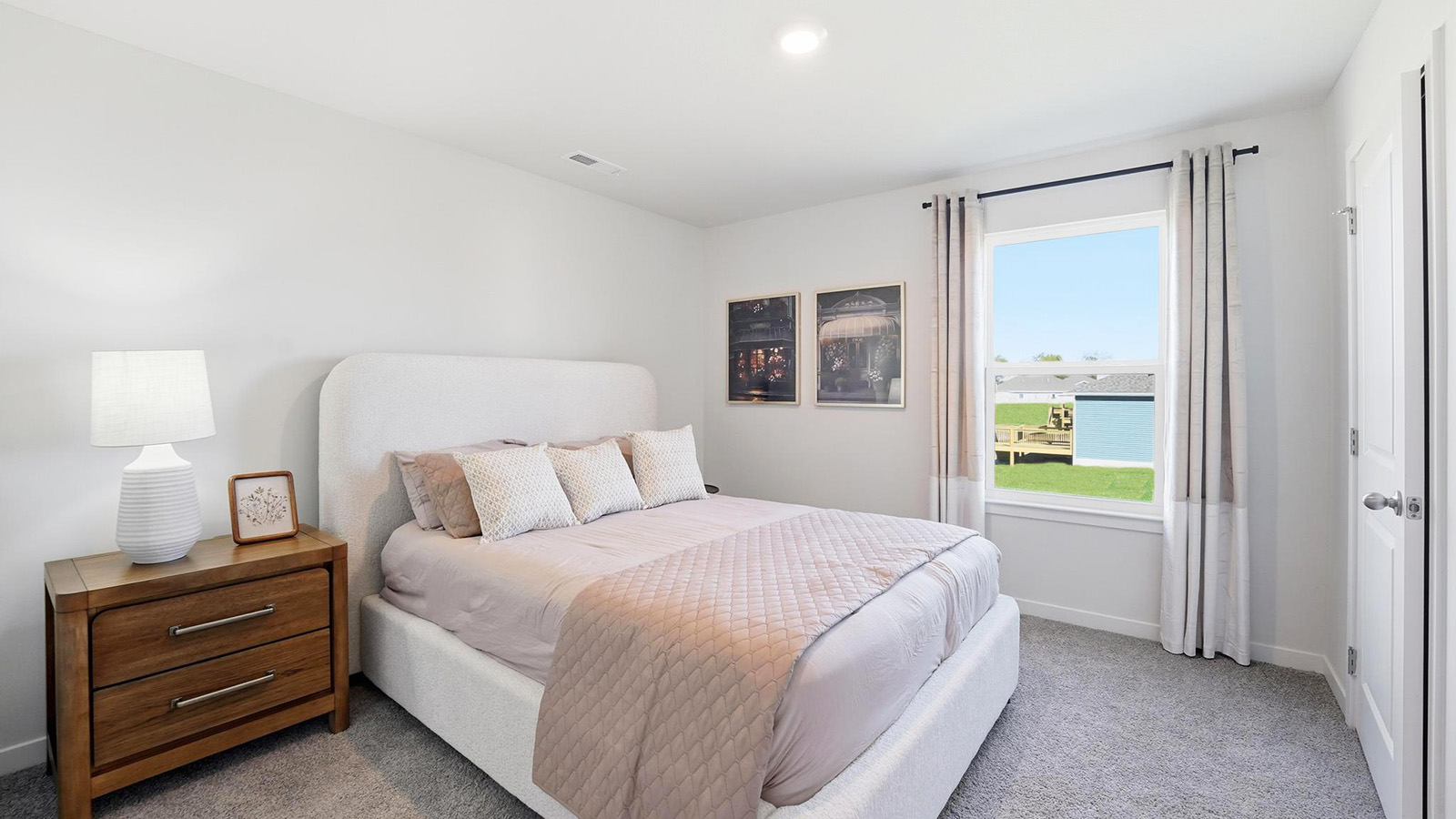 Carpeted bedroom with large window.