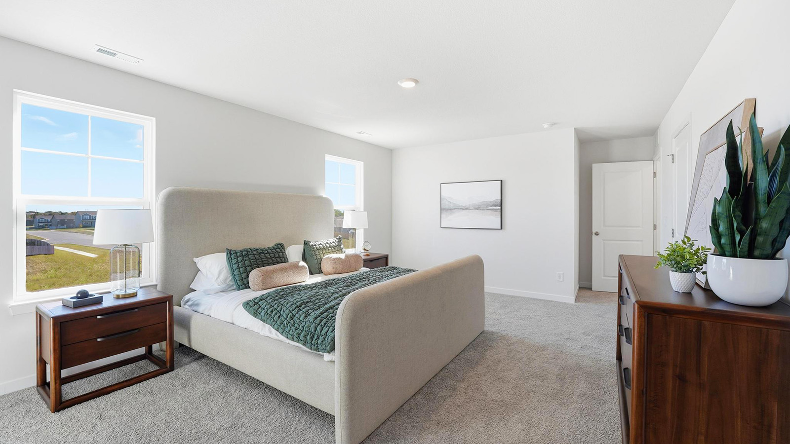 Carpeted primary bedroom with large windows and seating area.