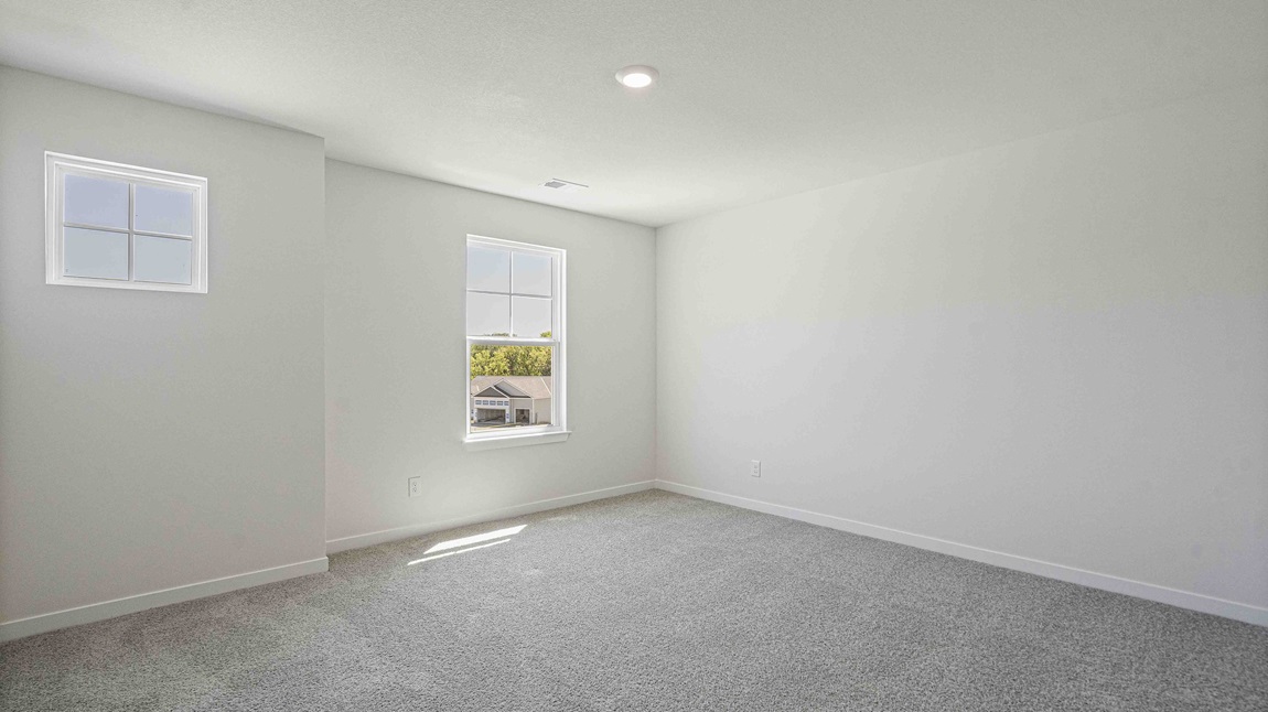 Carpeted bedroom with small window.