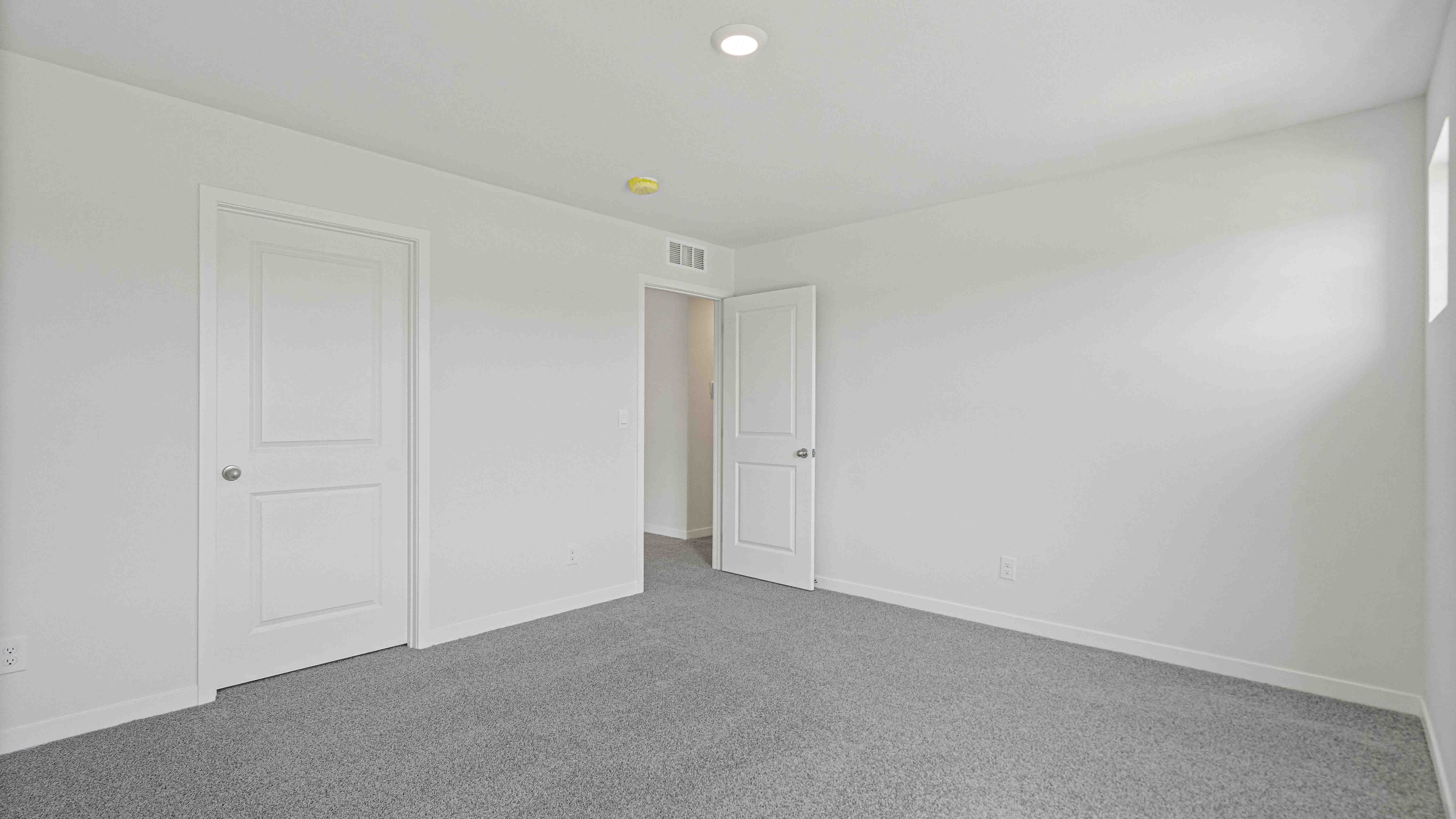 Carpeted bedroom with small window.