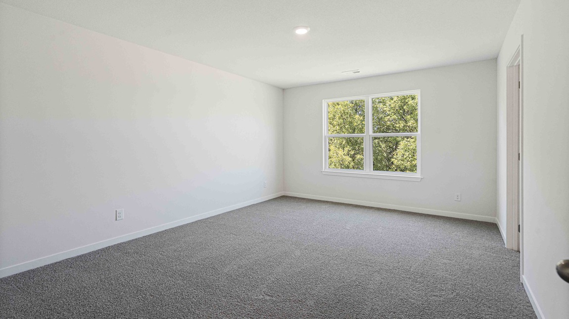 Primary bedroom carpeted with large window