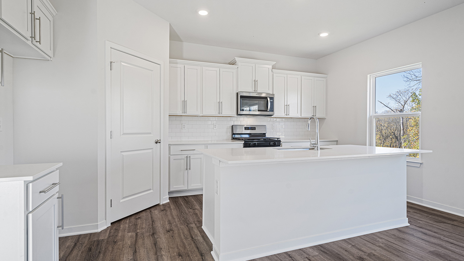Kitchen with large island, white cabinets and countertops and stainless steel appliances