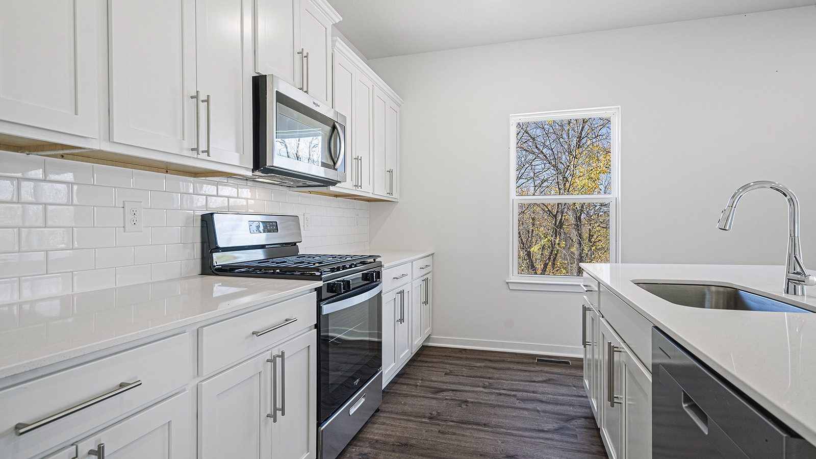 Kitchen with large island, white cabinets and countertops and stainless steel appliances