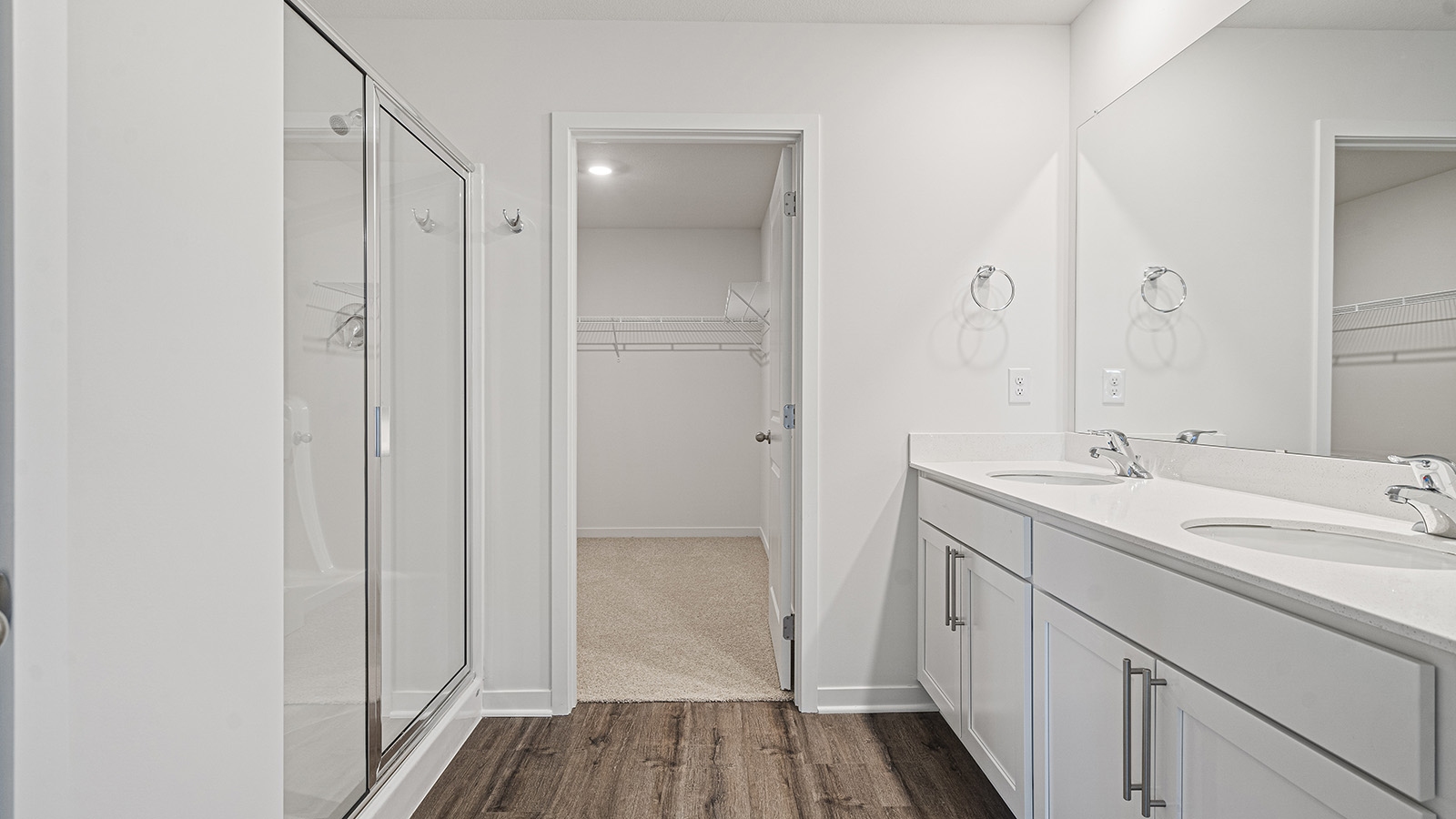 Primary bathroom with double vanity and glass door shower