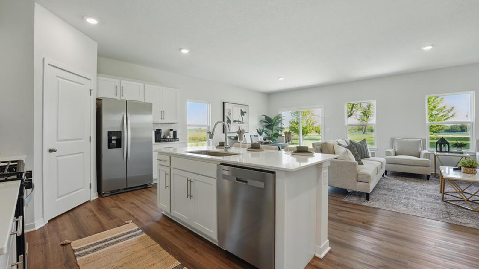 Open concept kitchen with large island, white cabinets and countertops, and stainless steel appliances