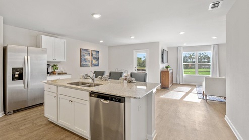 Large kitchen island with white cabinets and Whirlpool stainless appliances