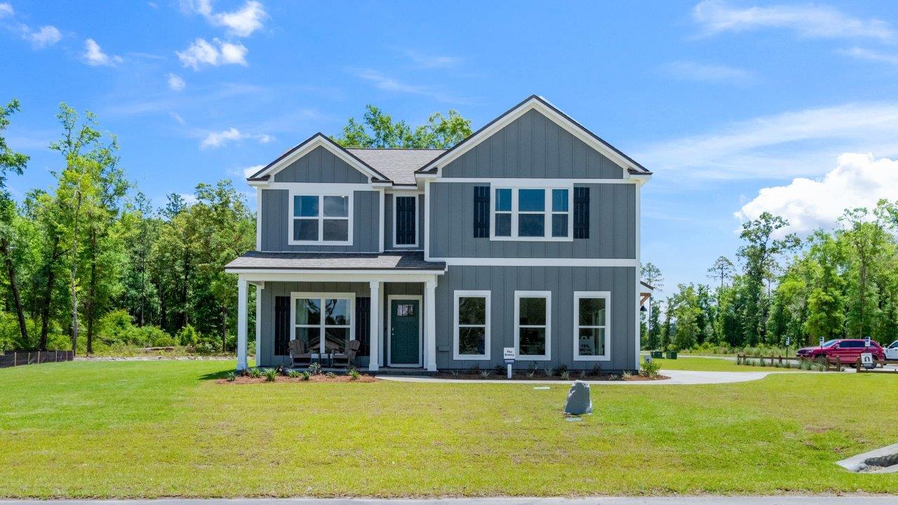 Exterior of the model home painted grey with black shutters on a large lot