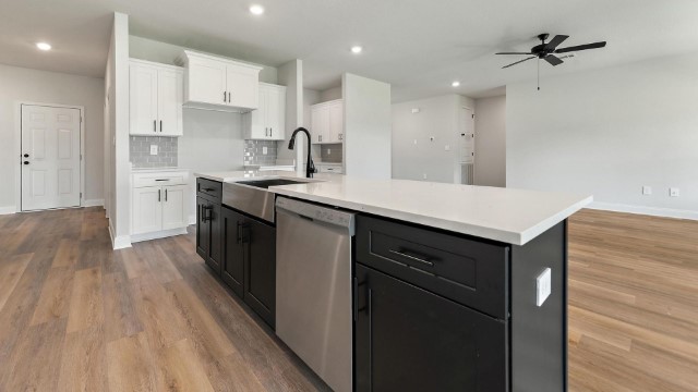 kitchen with island, stainless-steel appliances, cabinets, hardwood floors, and recessed lighting