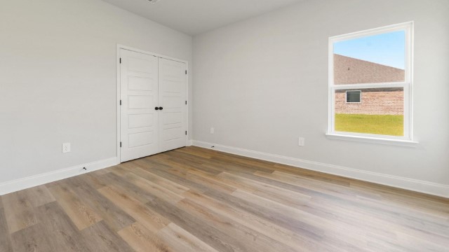 second bedroom with hardwood floors and window