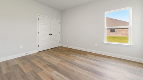 second bedroom with hardwood floors and window