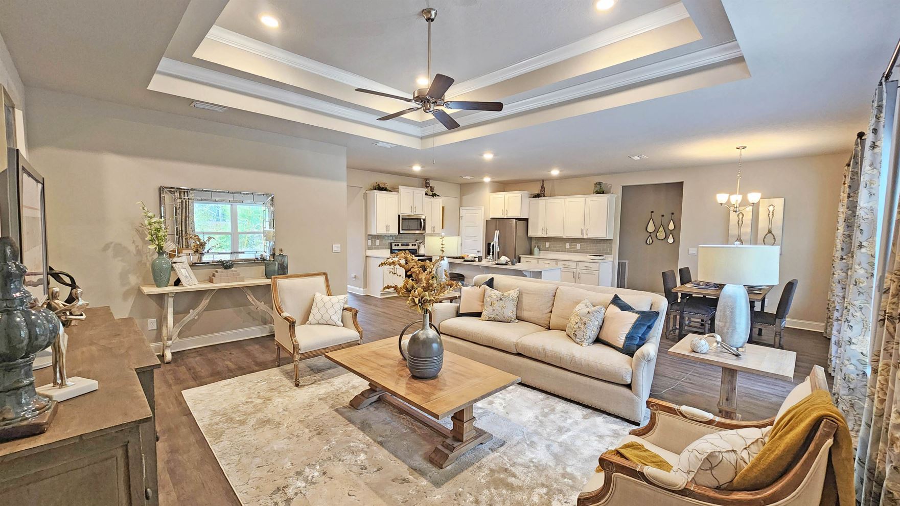living space with tray ceilings, hardwood floors, and ceiling fan