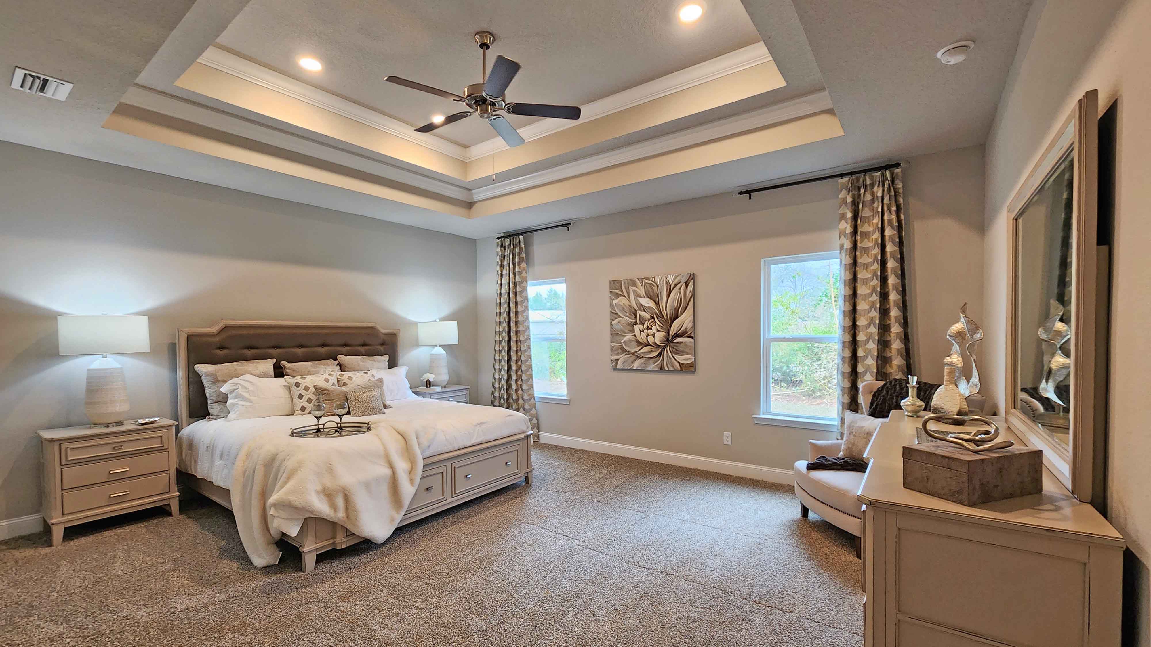primary bedroom with carpeted floors, tray ceilings, and ceiling fan