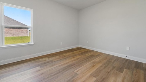 third bedroom with hardwood floors and window
