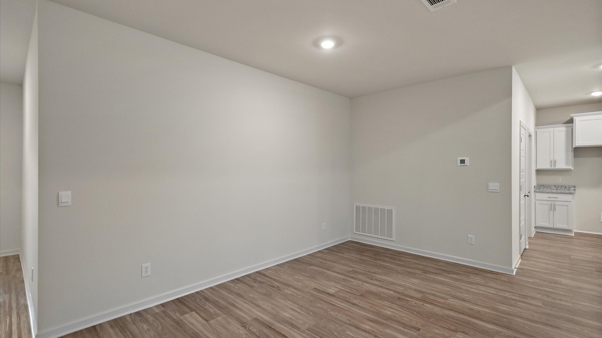 The dining room with recessed lighting and hardwood.