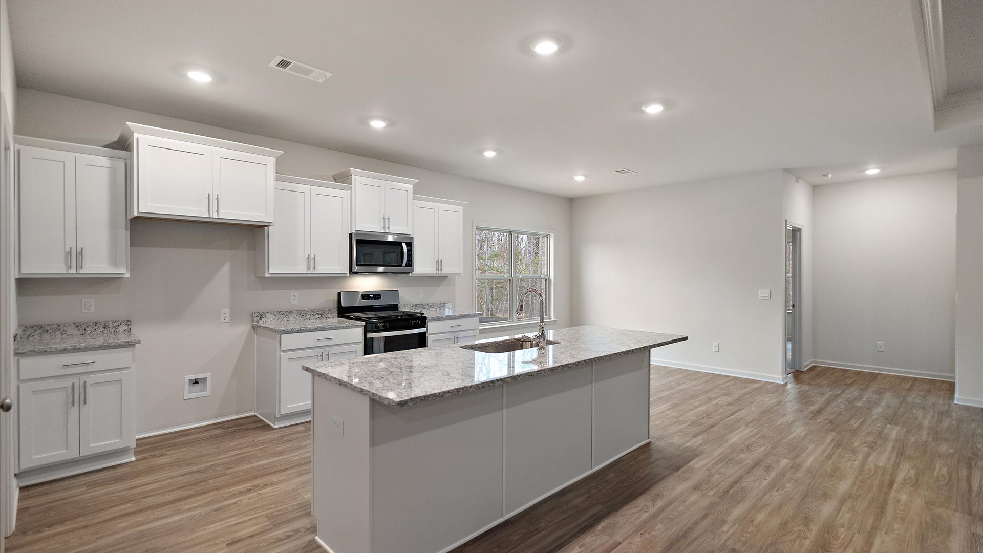 Spacious kitchen with granite countertops, island, and stainless-steel appliances.